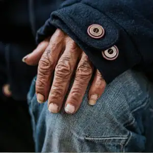Elderly person's hand resting on their knee, symbolizing neglect or vulnerability in a care facility.