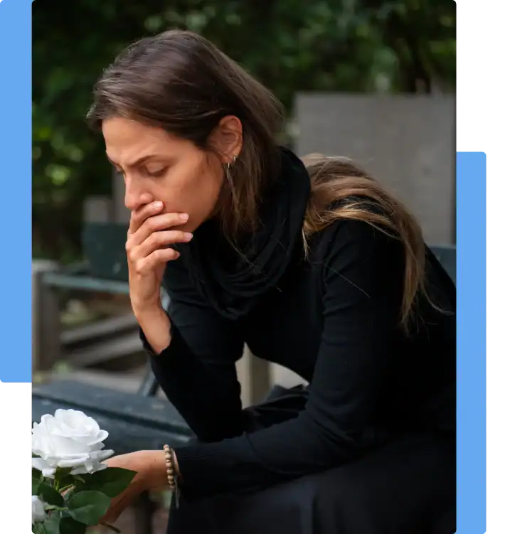 Grieving woman in black sitting at a cemetery with a white rose, mourning the wrongful death of a loved one
