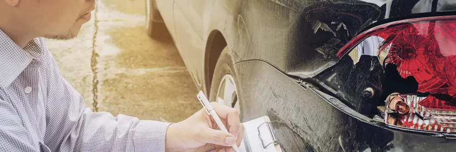 vehicle crash: man making notes about his car dented by an accident